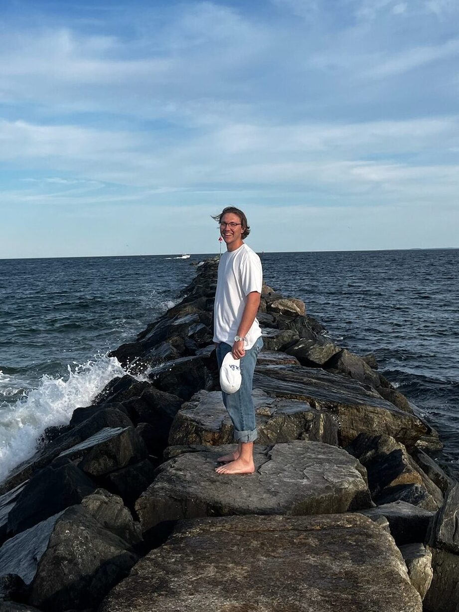 Waldau Literature's author standing on rocks in the ocean.
